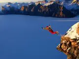 base jumper en vol au-dessus d'un lac alpin entouré de montagnes enneigées