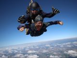 deux parachutistes en tandem effectuant un saut en chute libre au-dessus des nuages